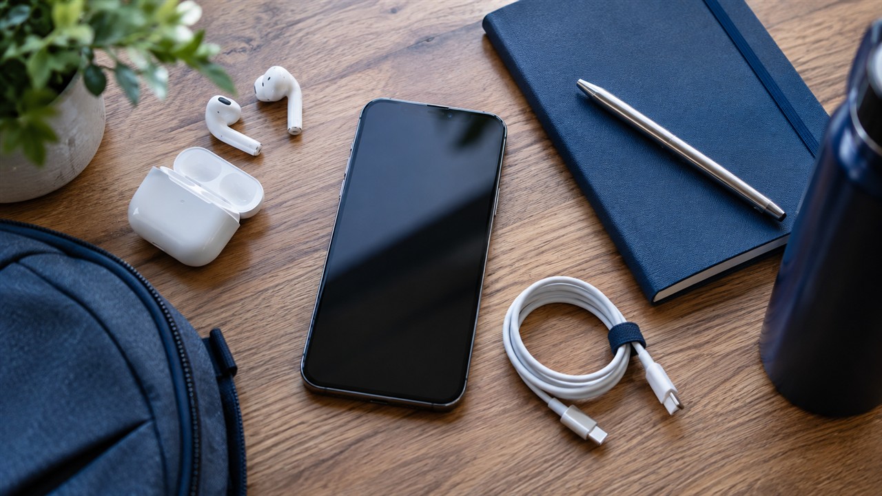 Un cellulare e delle cuffie blu sono appoggiati su un tavolo, pronti per ascoltare contenuti durante un viaggio.