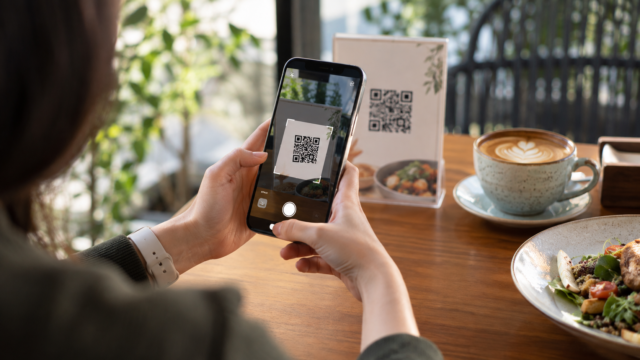 Pessoa usando a câmera do celular para escanear um código QR em um cartão.